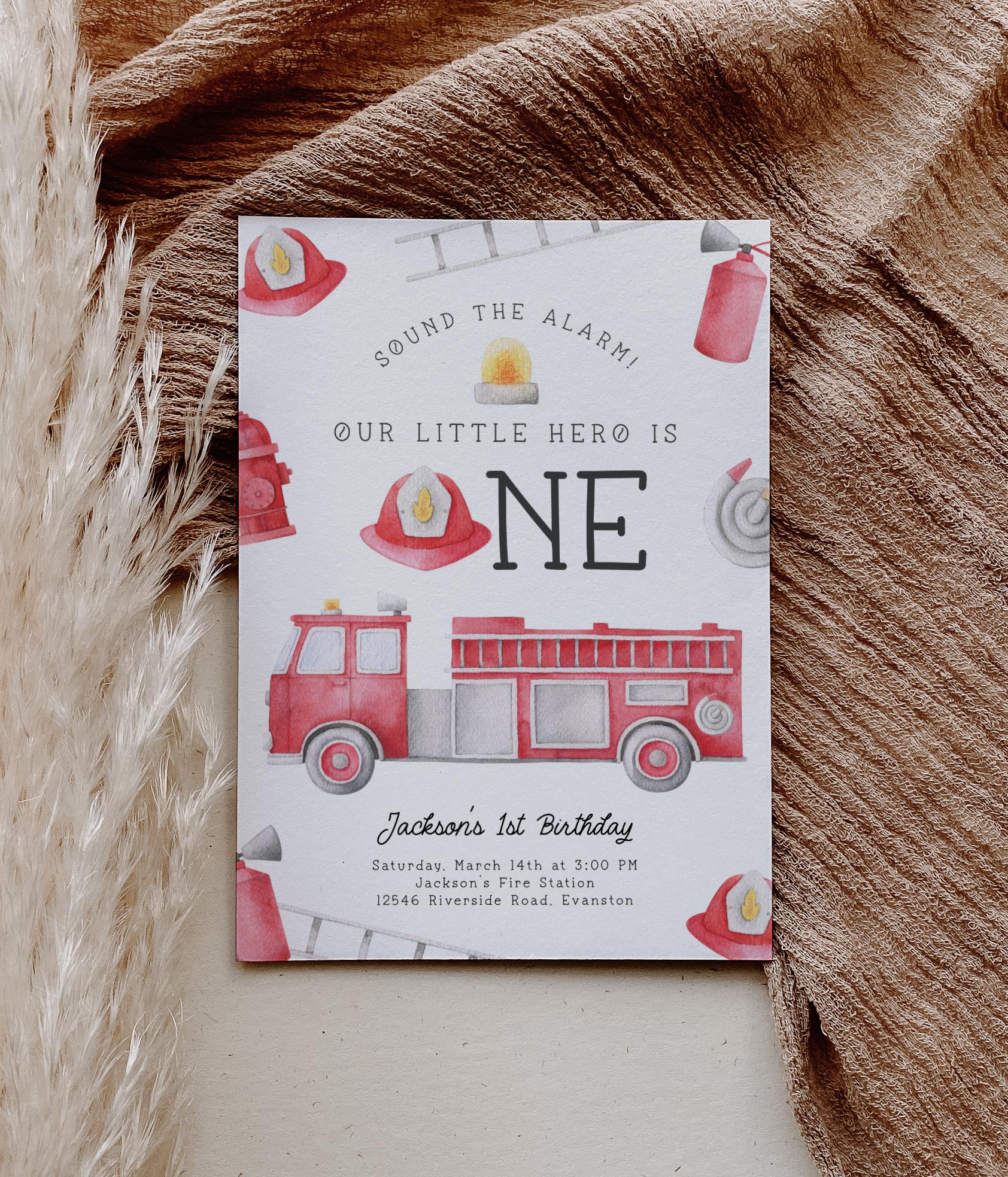 firetruck first birthday party invitation with playful watercolor graphics of firetruck, hose, hat, ladder, hydrant, extinguisher and siren light.  Reads "sound the alarm! Our little hero is ONE".  A fireman's hat is used in place of the "o" in ONE.