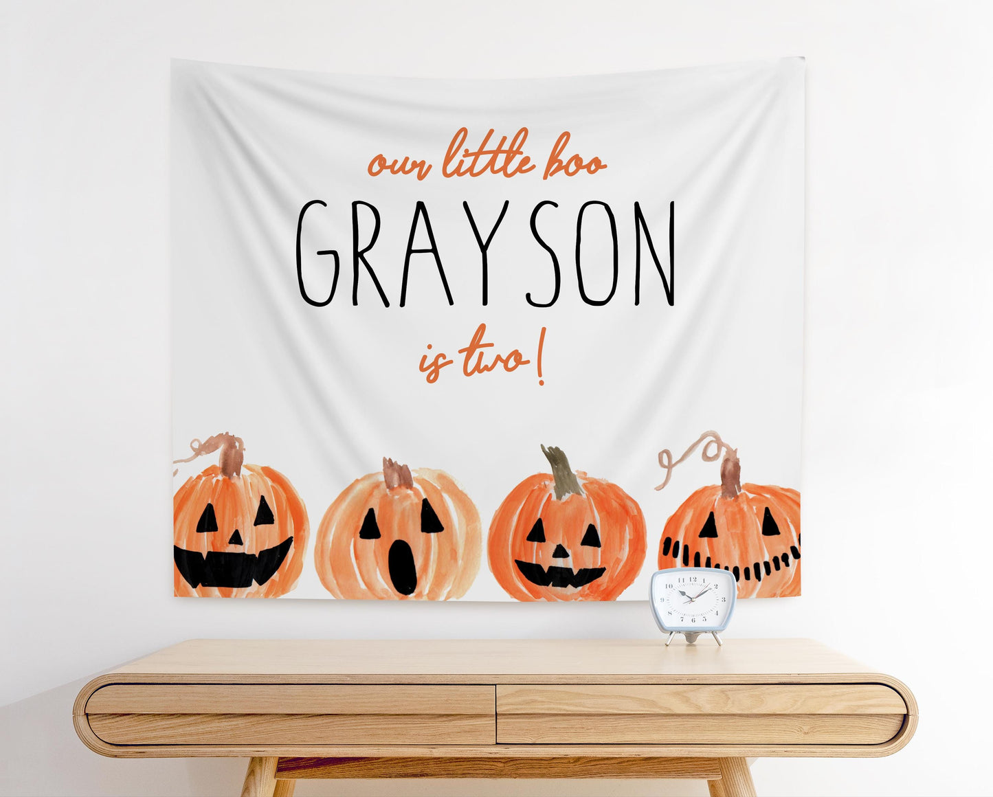 our little boo is two halloween 2nd birthday party fabric backdrop.  minimalist design with white background and playful jack o lantern pumpkin graphics along the bottom edge.