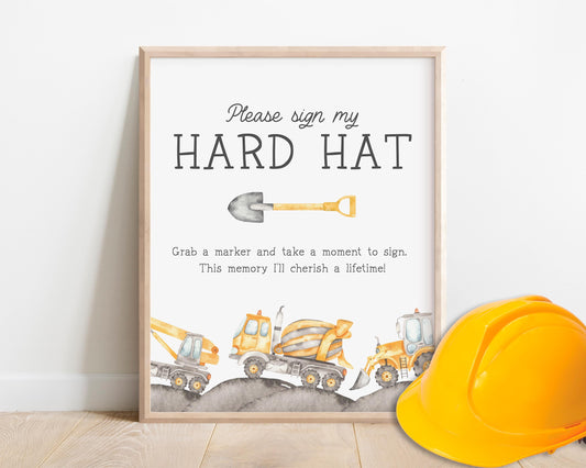 Construction-themed sign for a hard hat signing station, featuring a framed design with watercolor construction vehicles (crane, cement mixer, bulldozer) and a shovel illustration. The text invites guests to &#39;Please sign my hard hat&#39;.