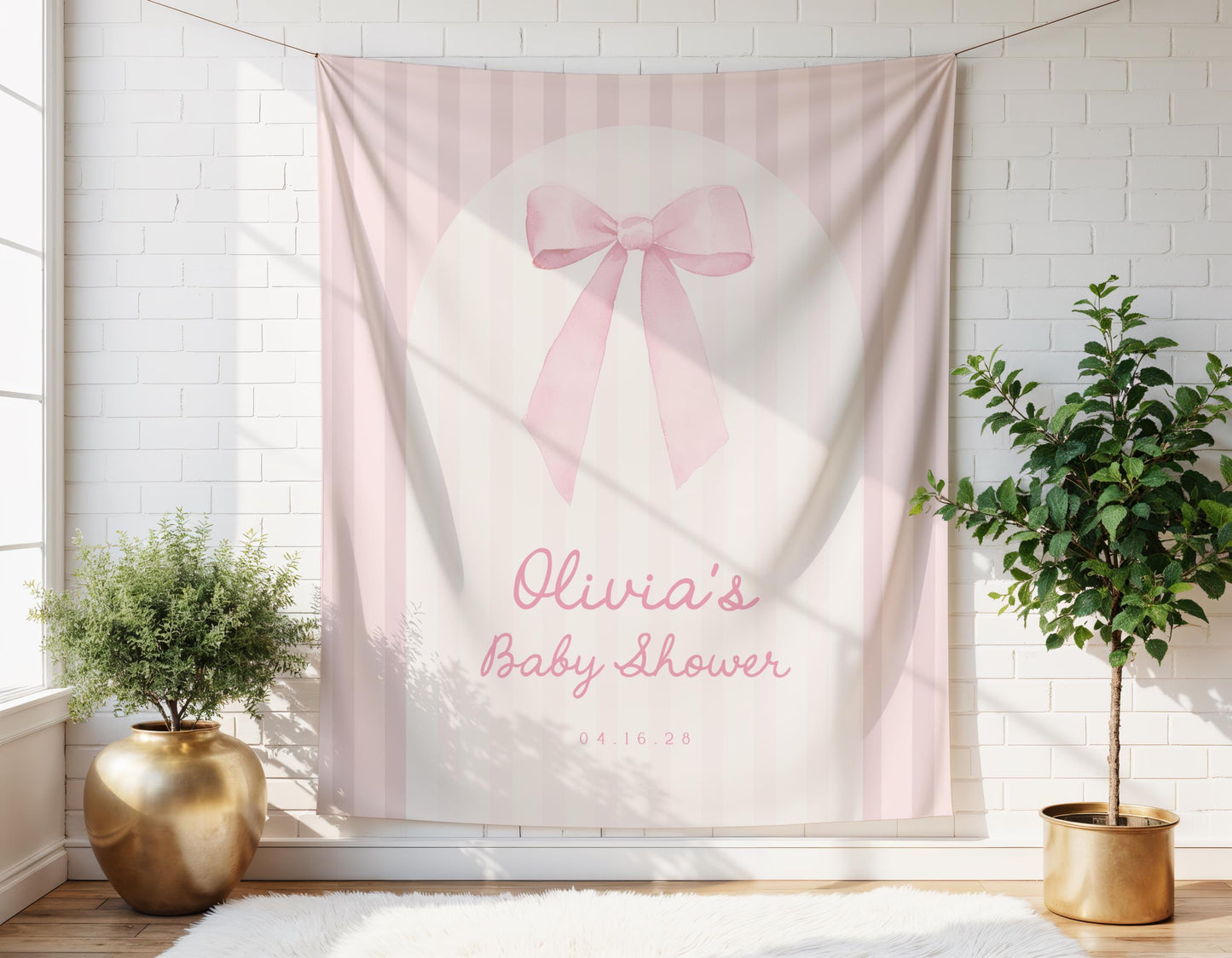 Pink striped baby shower arch backdrop with bow design.