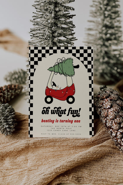 christmas first birthday invitation with red toy car hauling a christmas tree.  black checkered pattern background.