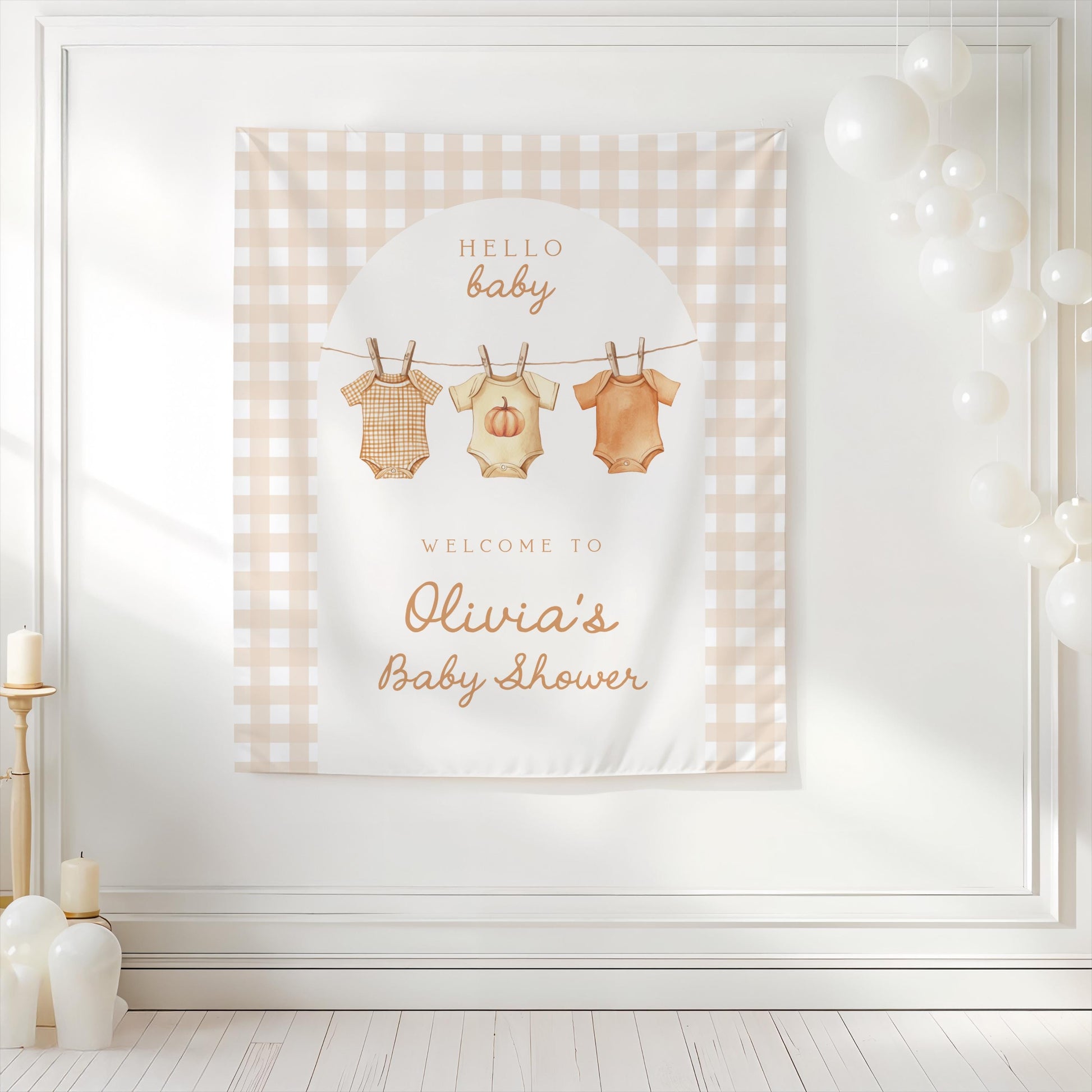 Neutral gingham baby shower backdrop with pumpkin onesies hanging on clothesline design, personalized with “Welcome to Olivia’s Baby Shower” and background decorated with white balloons.