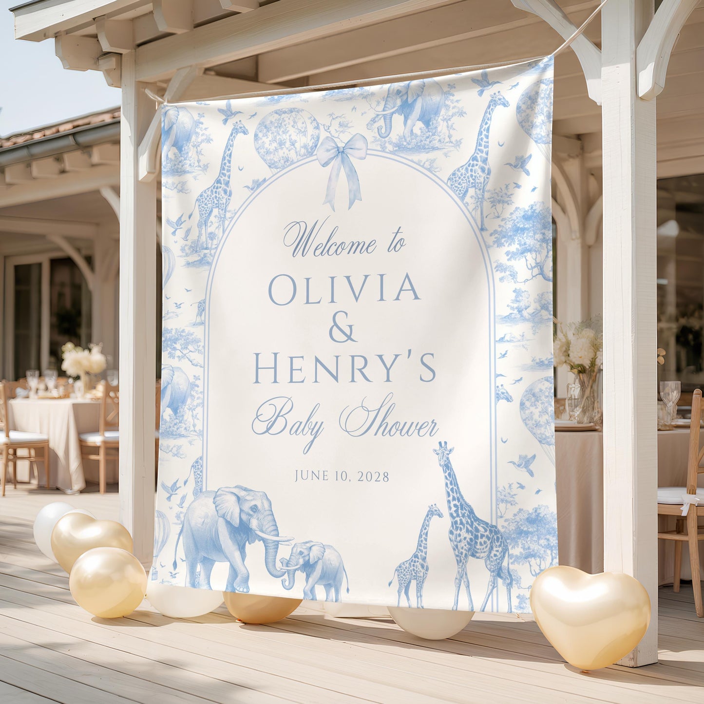 Blue safari toile baby shower backdrop with elegant giraffes and elephants in soft blue tones, featuring “Welcome to Olivia & Henry’s Baby Shower” printed design displayed outdoors with gold and white balloons.