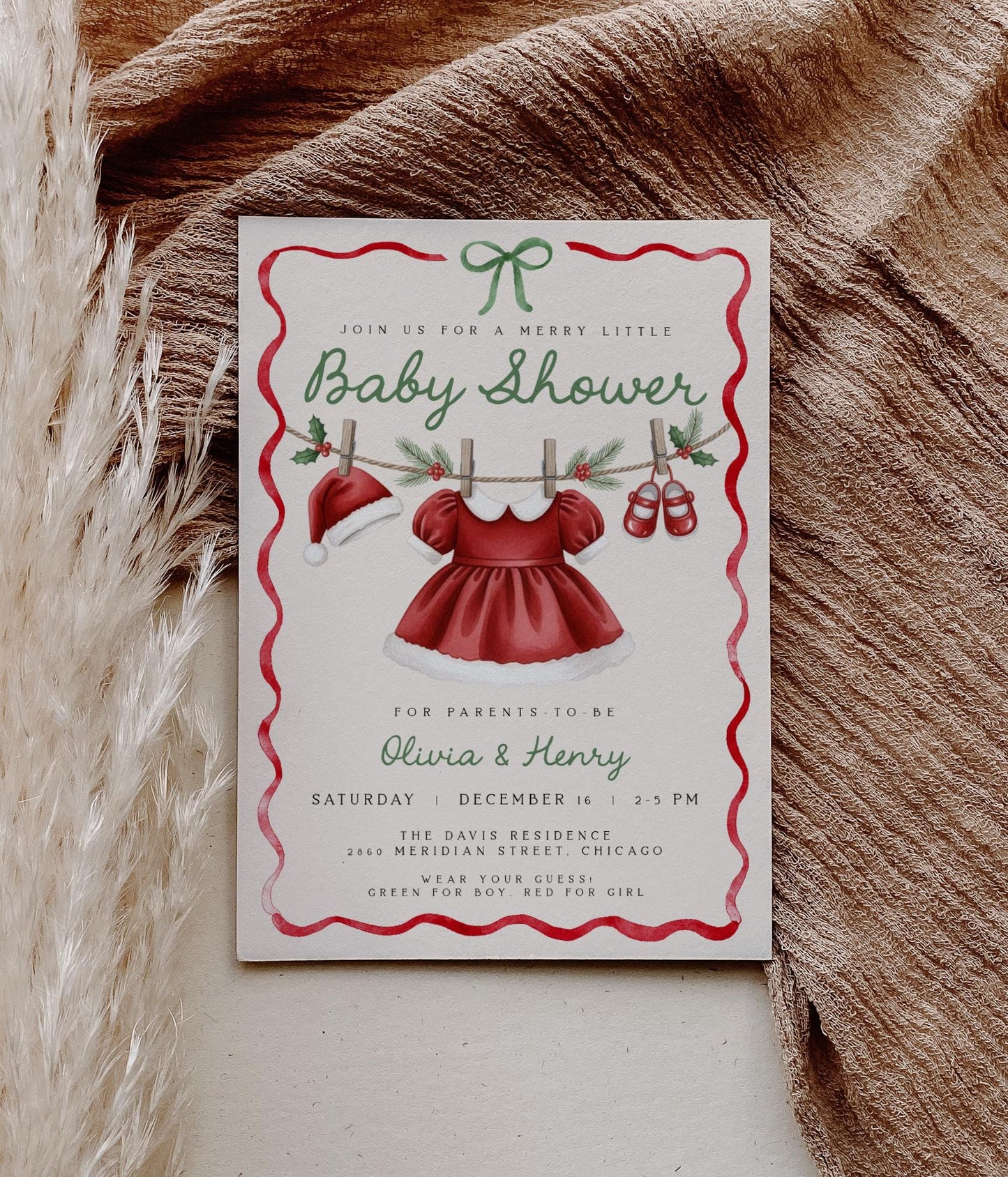 girl christmas baby shower invitation featuring santa hat, dress and shoes on clothesline.  red wavy ribbon border with green coquette bow.