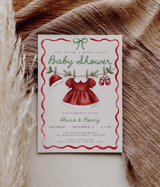 girl christmas baby shower invitation featuring santa hat, dress and shoes on clothesline.  red wavy ribbon border with green coquette bow.
