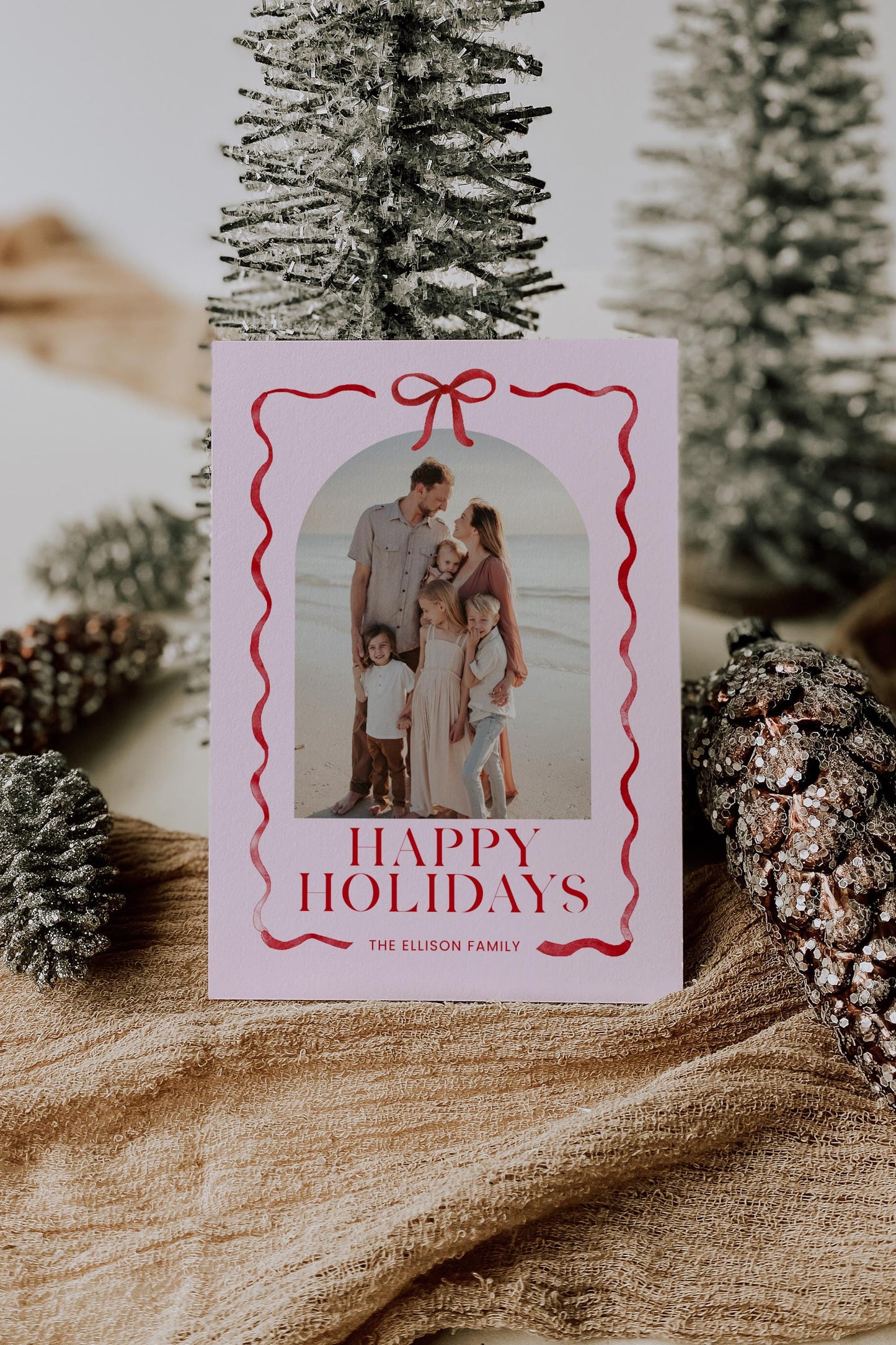 pink and red christmas photo card with bow and ribbon outline, reads "happy holidays, the ellison family"