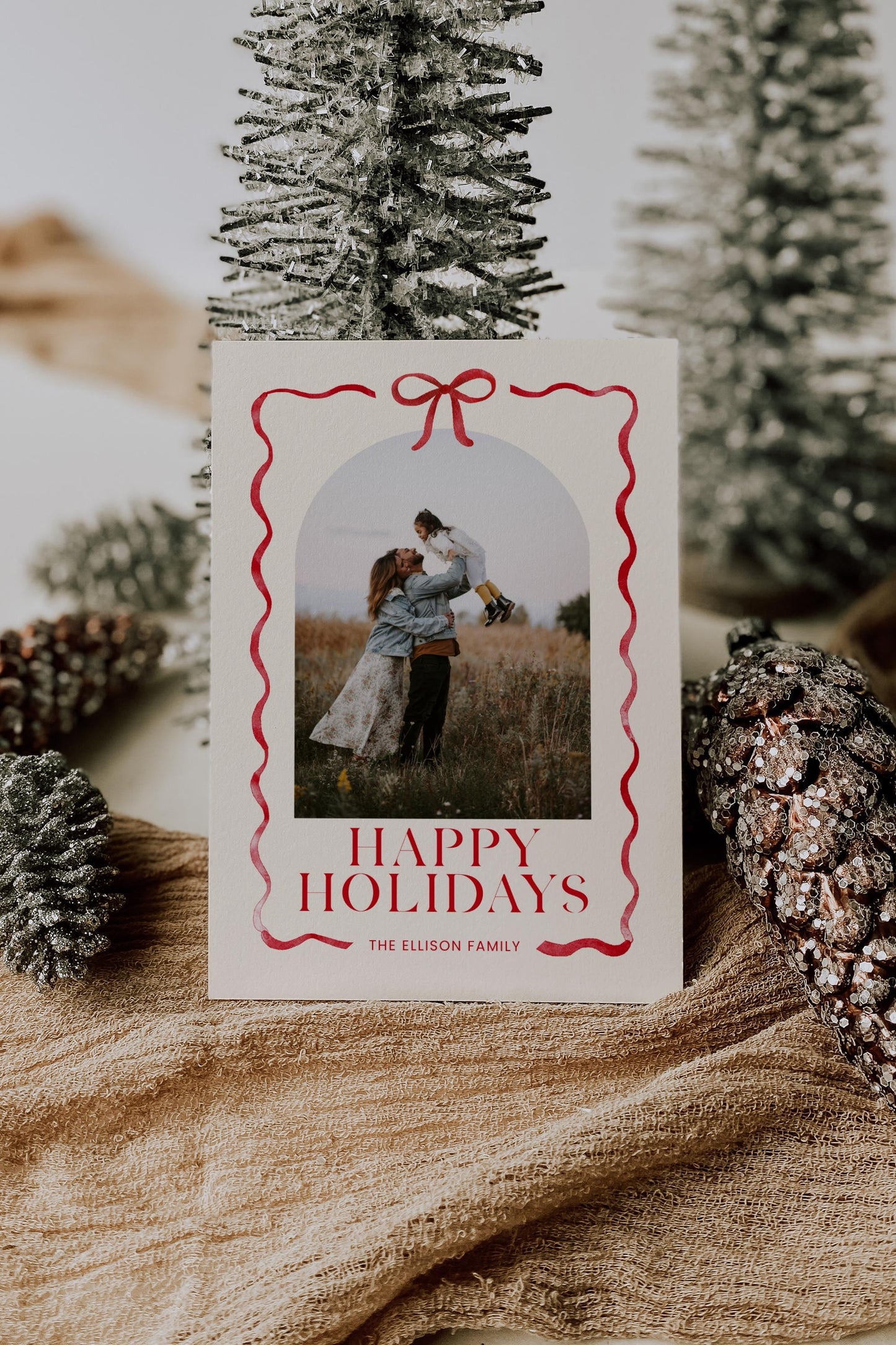 holiday photo card natural beige cream background with red bow and ribbon surrounding photo.  reads &quot;happy holidays, the ellison family&quot;