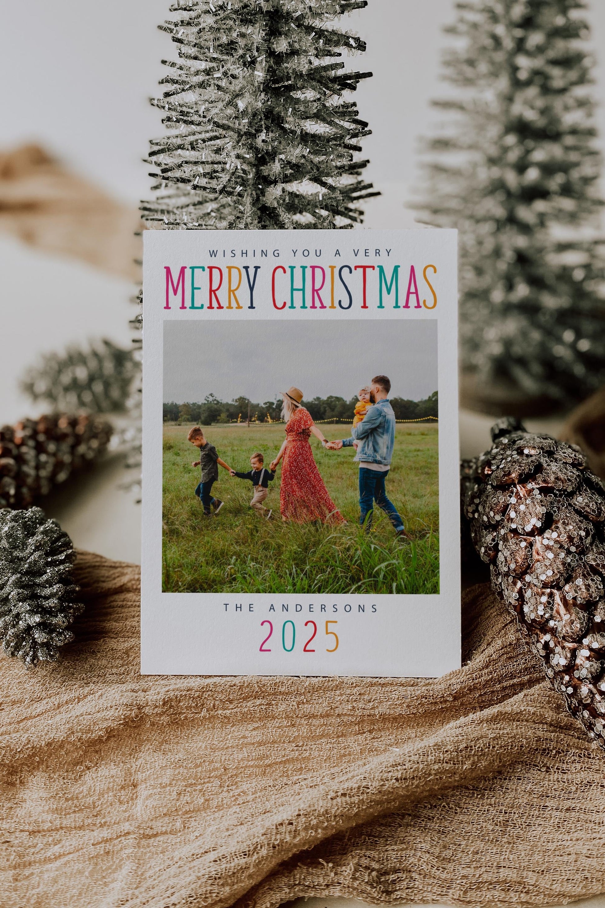 Colorful photo christmas card with pink, turquoise, navy, red, orange lettering.  square photo in center.  reads "wishing you a very MERRY CHRISTMAS" above photo.  Reads "THE ANDERSONS" below photo with the year.