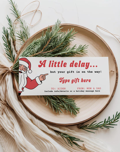 certificate for christmas present that has been delayed.  Santa graphic pointing to text that reads "a little delay....but your gift is on the way!"