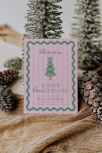 pink green winter onederland first birthday invitation with pink stripe background a sage green wavy border.  graphic of christmas tree with bow on top.