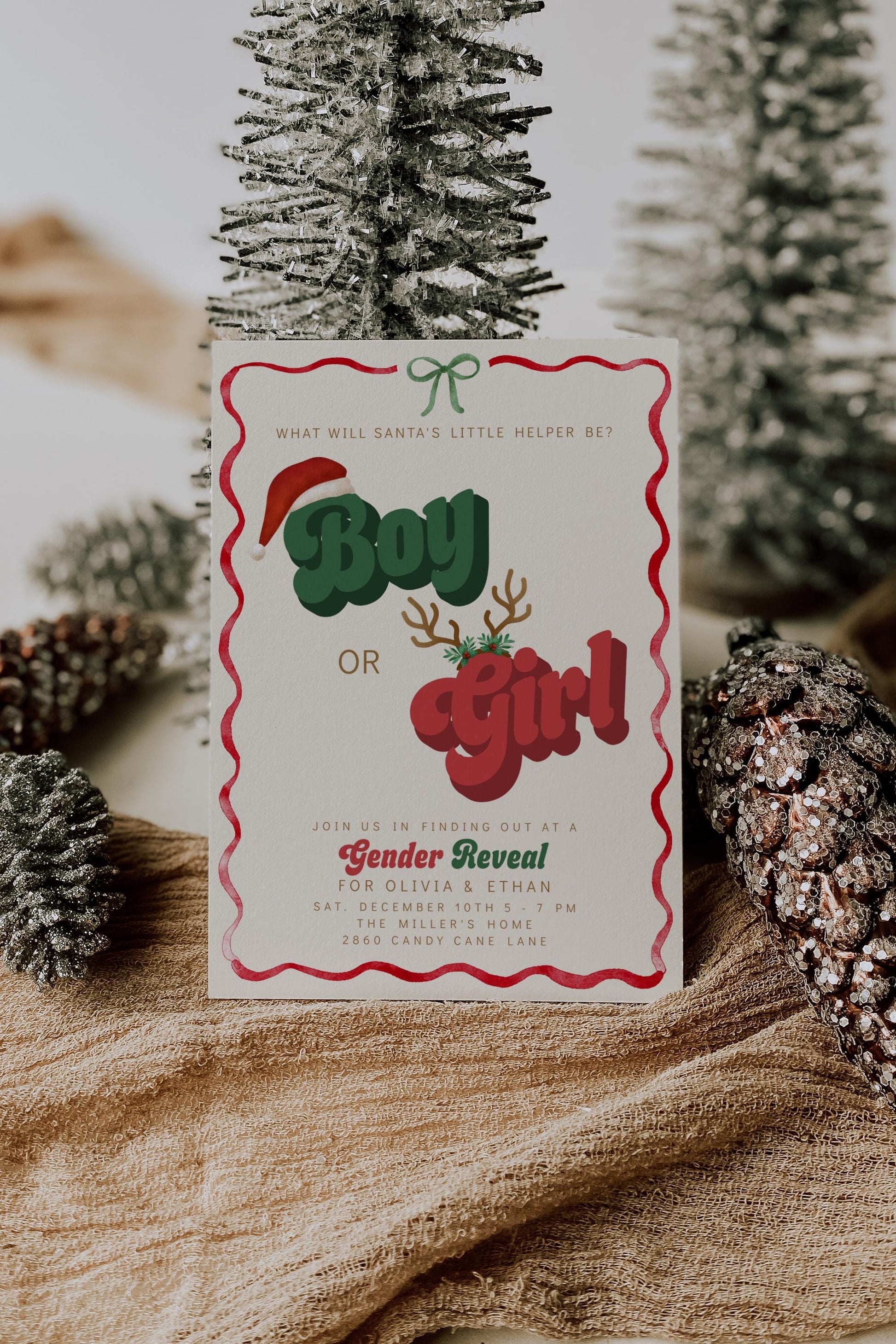Christmas gender reveal invitation with retro red and green text reading “Boy or Girl,” featuring Santa hat, antlers, and wavy red border on a cream background.