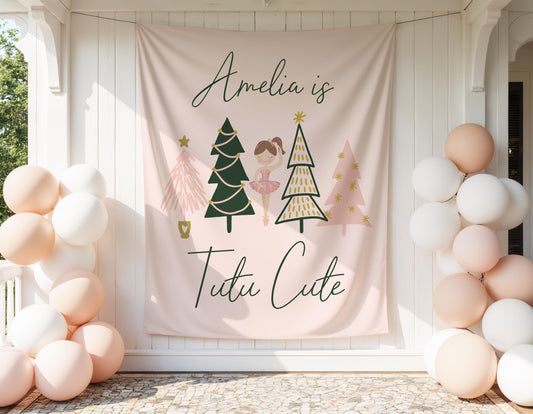 tutu cute 2nd birthday backdrop in pale pink, peach, gold and green.  large fabric banner with whimsical christmas tree graphics and a ballerina girl centered in middle.  Reads &quot;Amelia is Tutu Cute&quot;